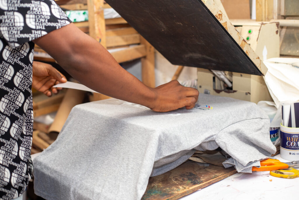 A man transferring DTF print on a T-Shirt using a heat press